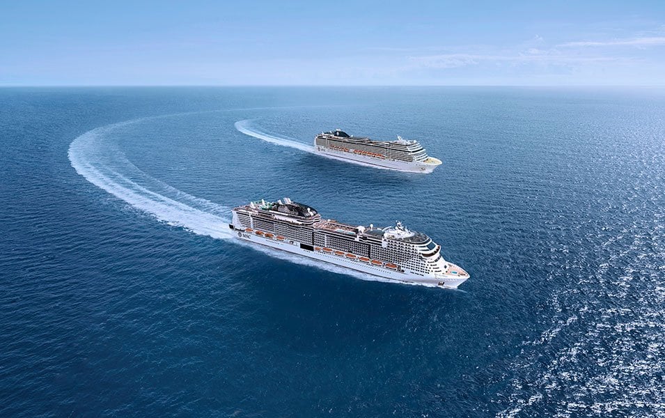 Two MSC cruise ships sailing in open blue waters under a clear sky | MSC Cruises Two MSC cruise ships sailing in open blue waters under a clear sky | MSC Cruises