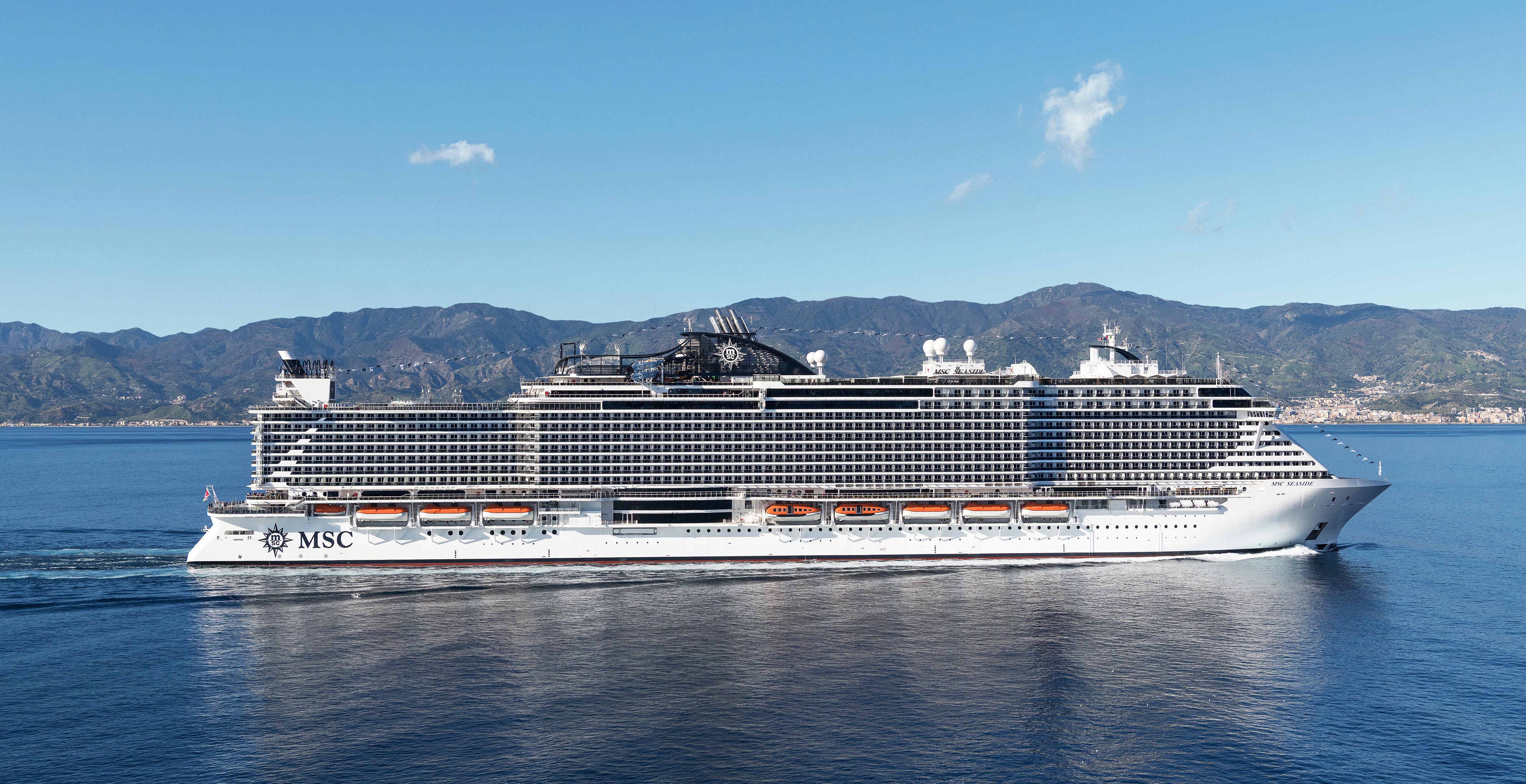 An MSC cruise ship sailing near a scenic coastline under a clear blue sky | MSC Cruises