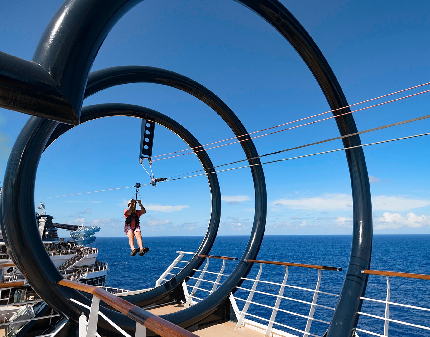 A guest ziplining through loops on a cruise ship deck with ocean views | MSC Cruises A guest ziplining through loops on a cruise ship deck with ocean views | MSC Cruises