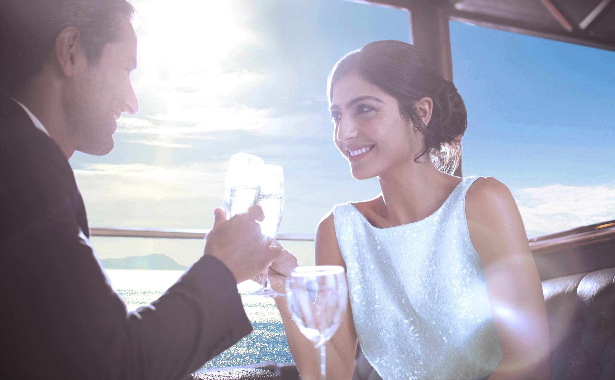 A couple toasting with glasses of sparkling water on a cruise deck under a sunny sky | MSC Cruises A couple toasting with glasses of sparkling water on a cruise deck under a sunny sky | MSC Cruises