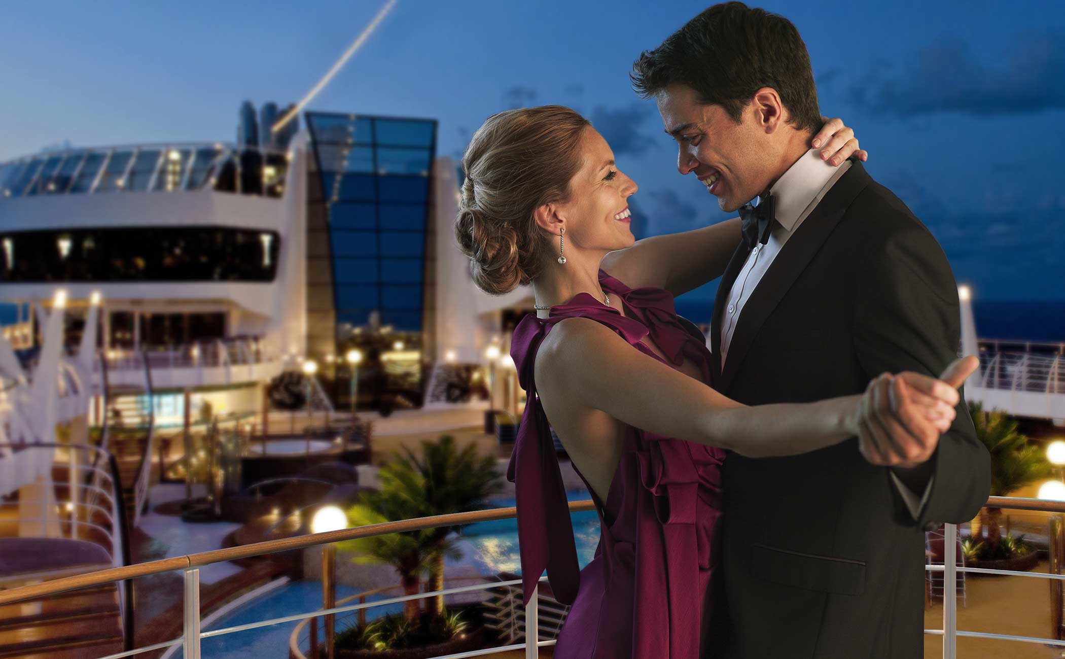 Elegantly dressed couple dancing on a cruise ship deck under the evening sky | MSC Cruises Elegantly dressed couple dancing on a cruise ship deck under the evening sky | MSC Cruises